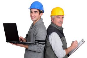 senior plumber and junior holding laptop and clipboard